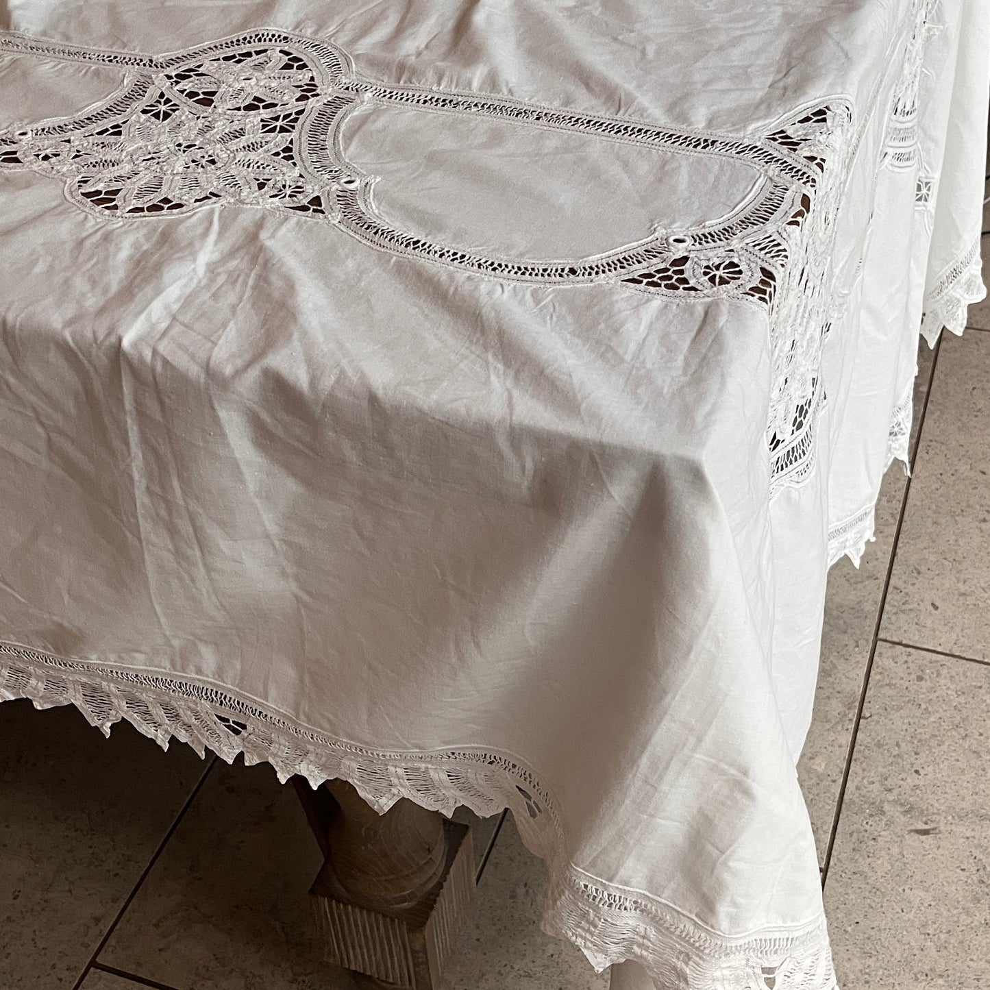 White lace dress on a tiled floor with a chair in the background