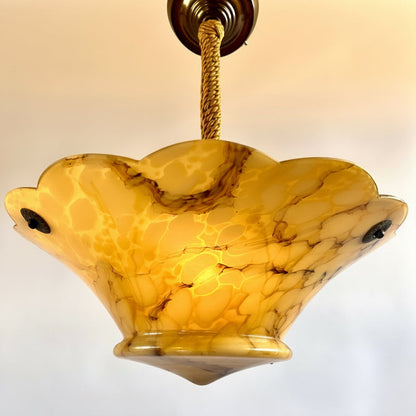 Decorative ceiling light fixture with a yellowish-brown marbled shade on a plain background