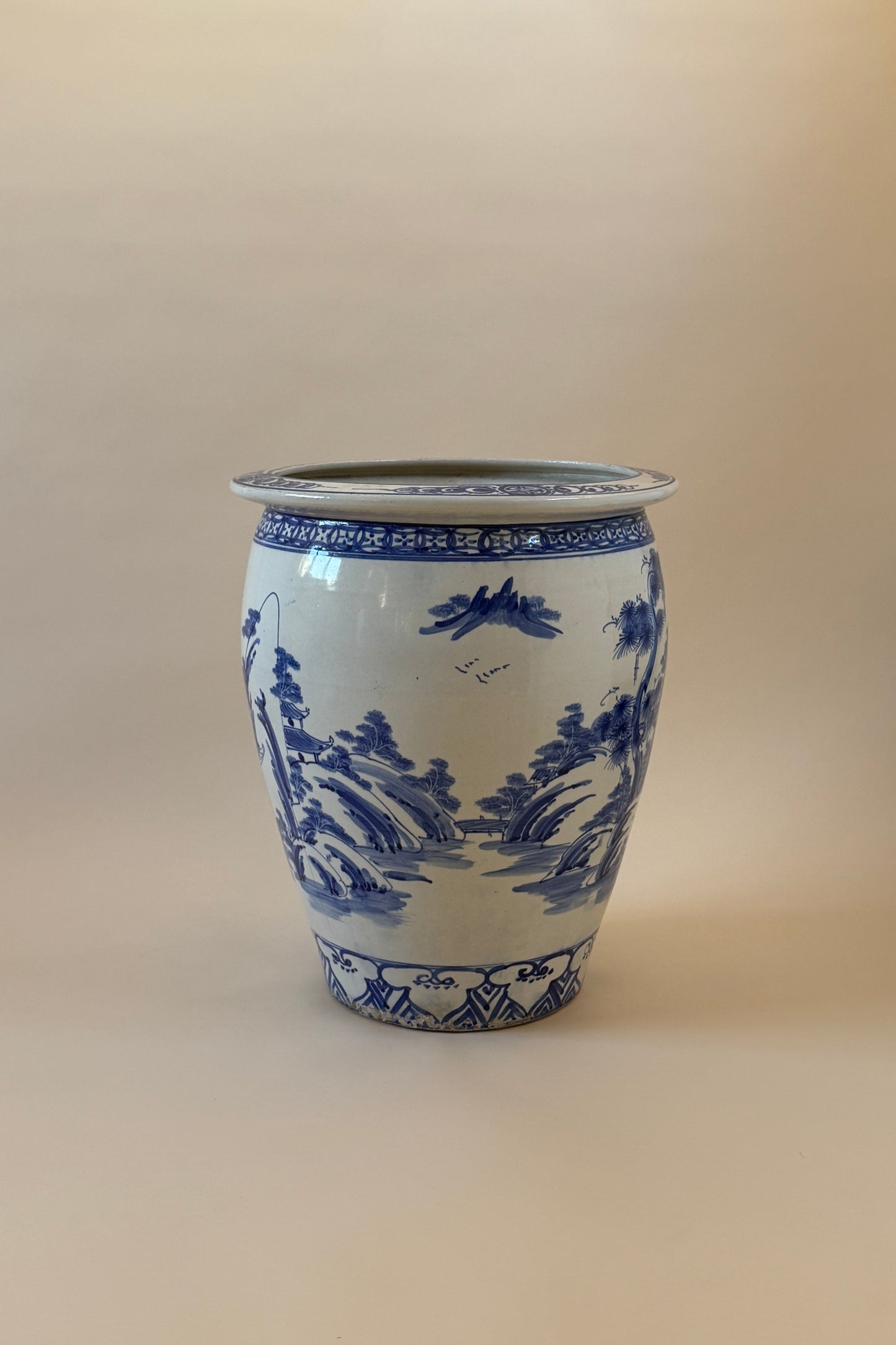 A classic blue and white porcelain vase featuring traditional Chinese landscape illustrations, set against a plain beige background.