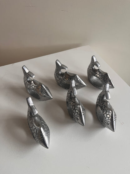 Set of silver decorative elements resembling animal shapes on a white surface