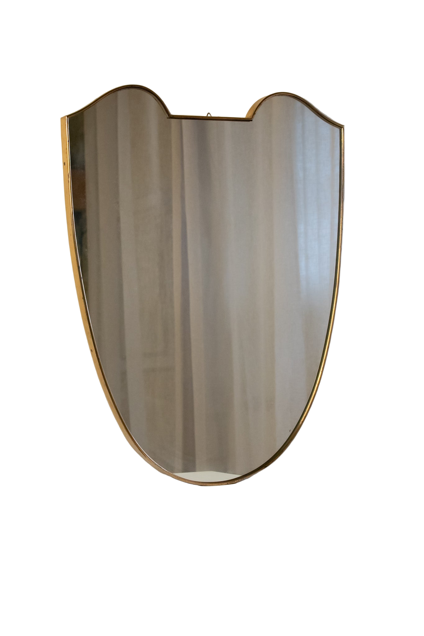 midcentury brass Italian
Shield-shaped mirror with brass frame on a white pedestal against a beige wall