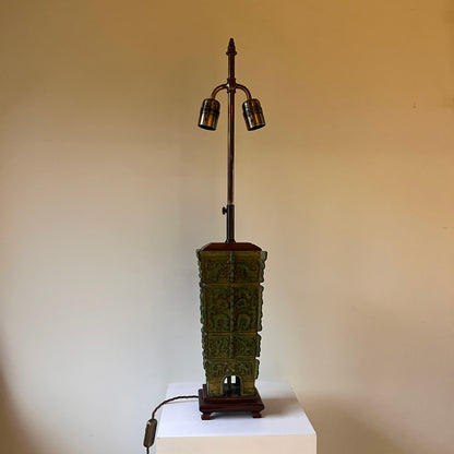 green Chinese archaic lamp base on brown feet with a neutral background