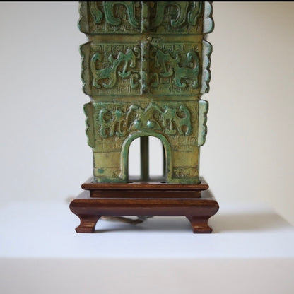 green Chinese archaic lamp base on brown feet with a neutral background