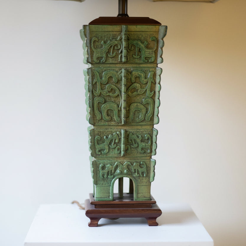 green Chinese archaic lamp base on brown feet with a neutral background
