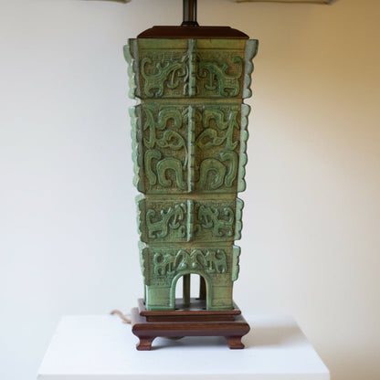 green Chinese archaic lamp base on brown feet with a neutral background