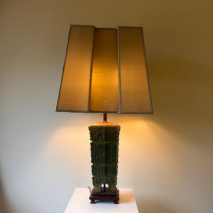 Chinese bronze table lamp turned on with a neutral background