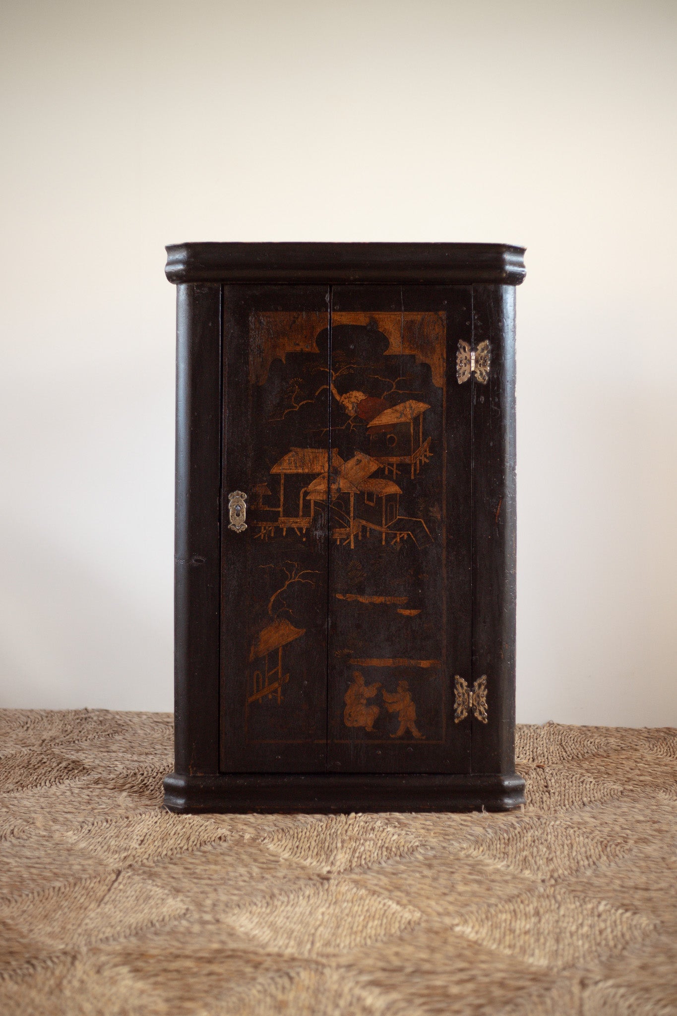 Decorative antique Georgian chinoiseriewooden cabinet with intricate carvings on a textured surface.
