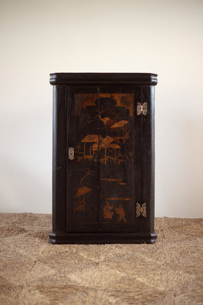 Decorative antique Georgian chinoiseriewooden cabinet with intricate carvings on a textured surface.