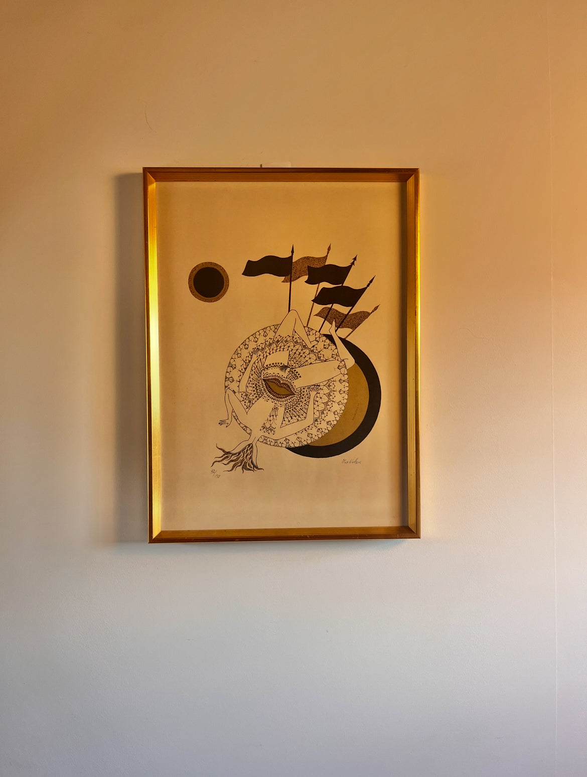 lithograph in a gold frame on a neutral wall