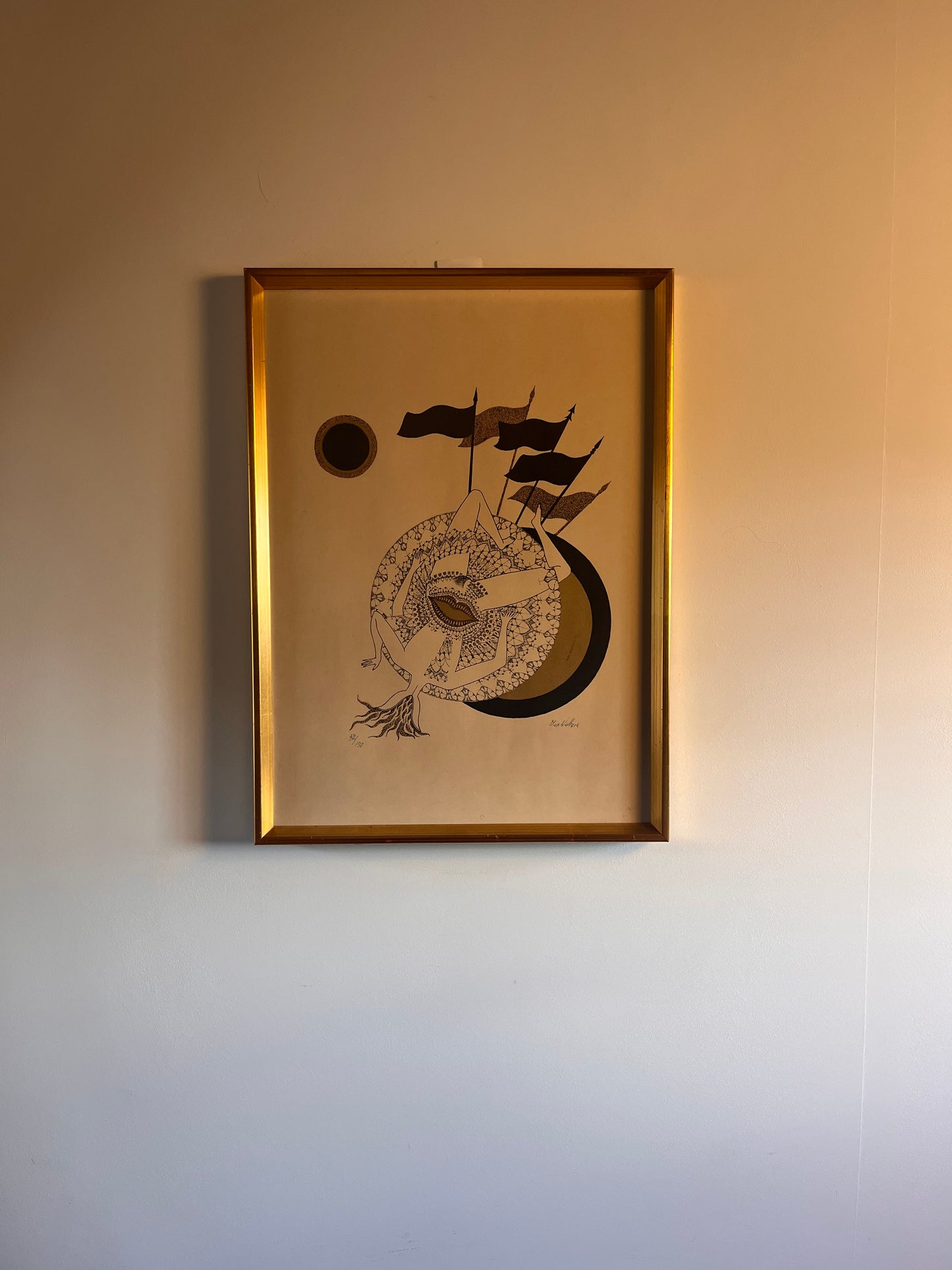 lithograph in a gold frame on a neutral wall