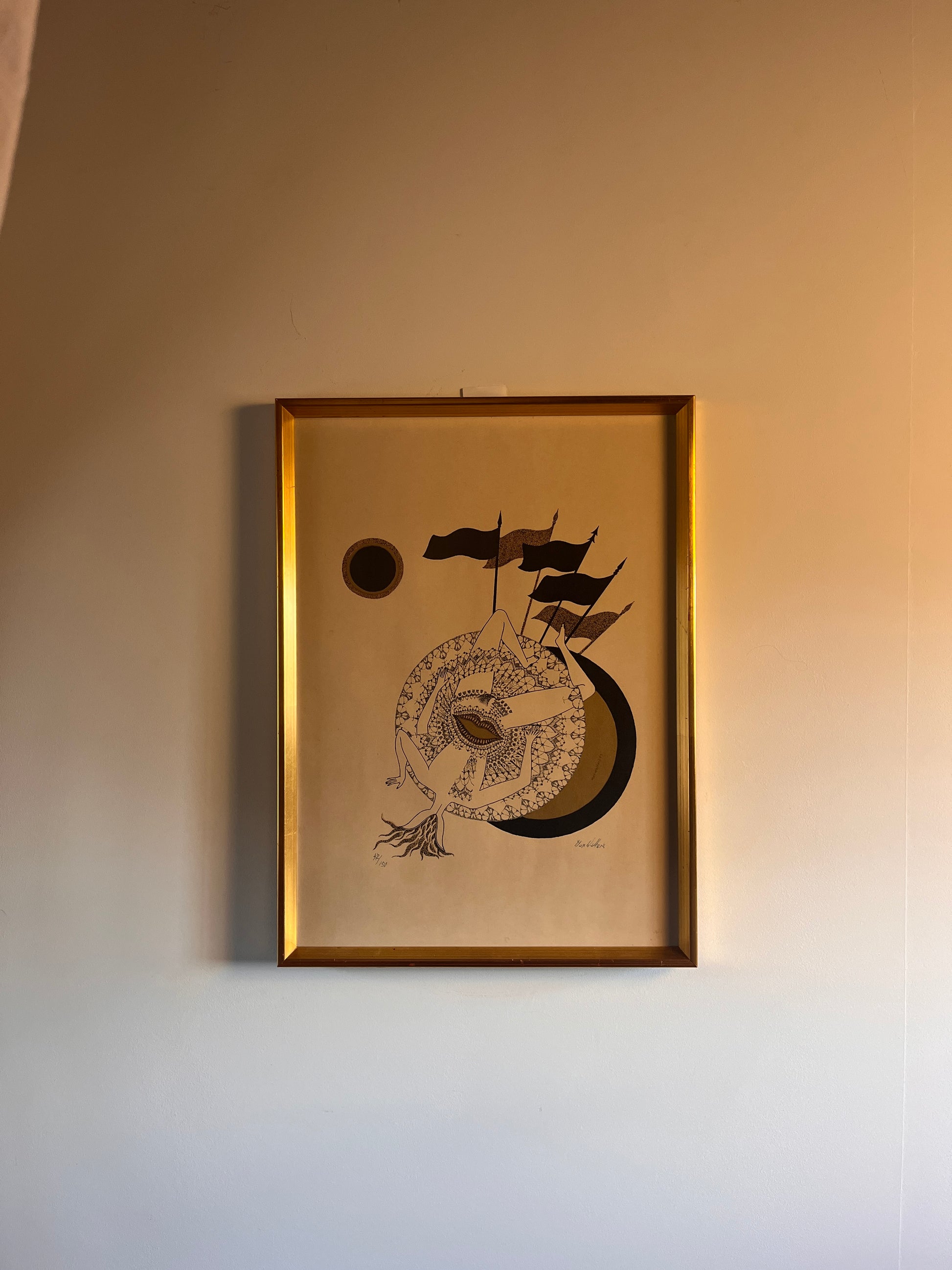 lithograph in a gold frame on a neutral wall