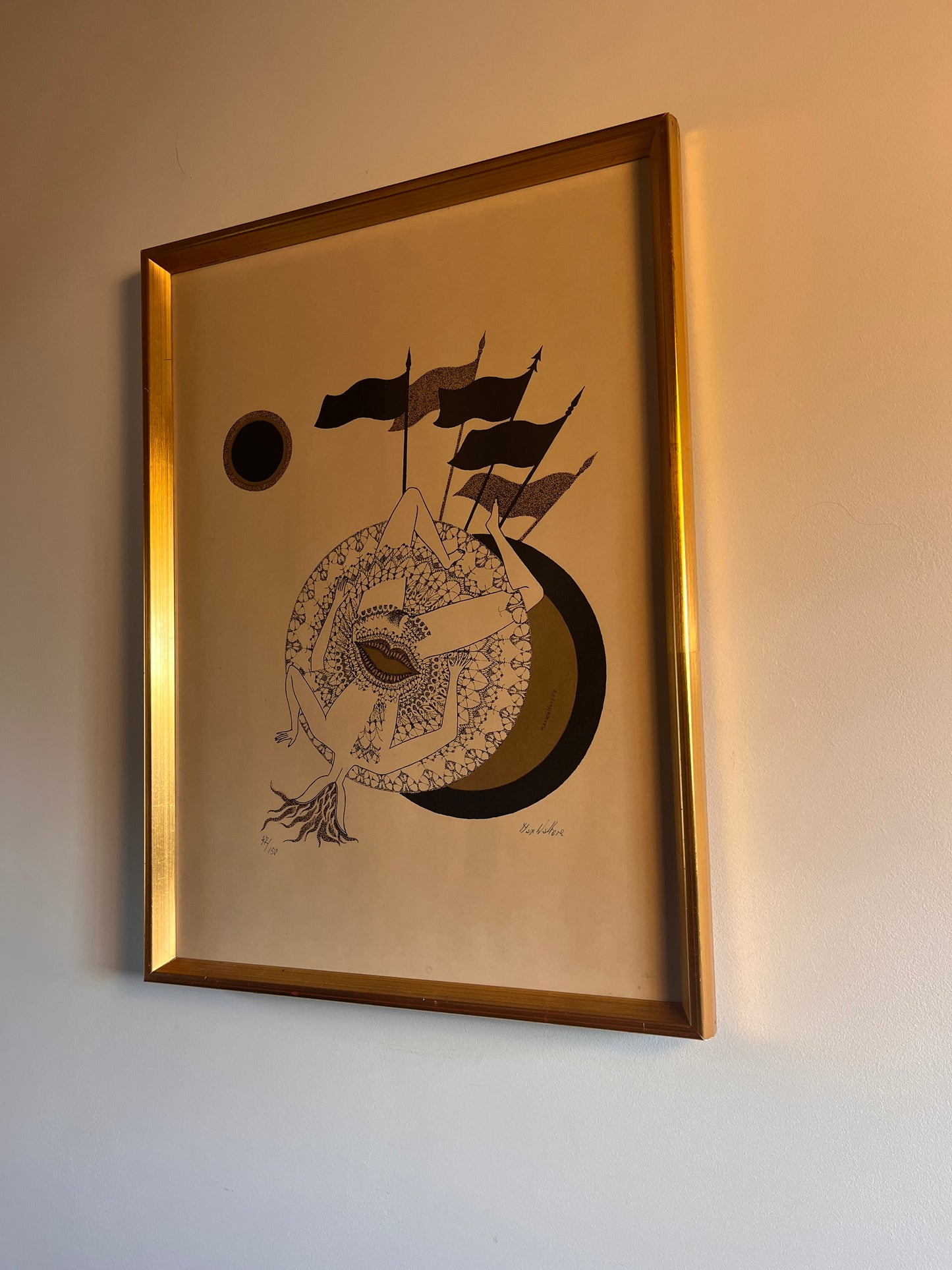 lithograph in a gold frame on a neutral wall