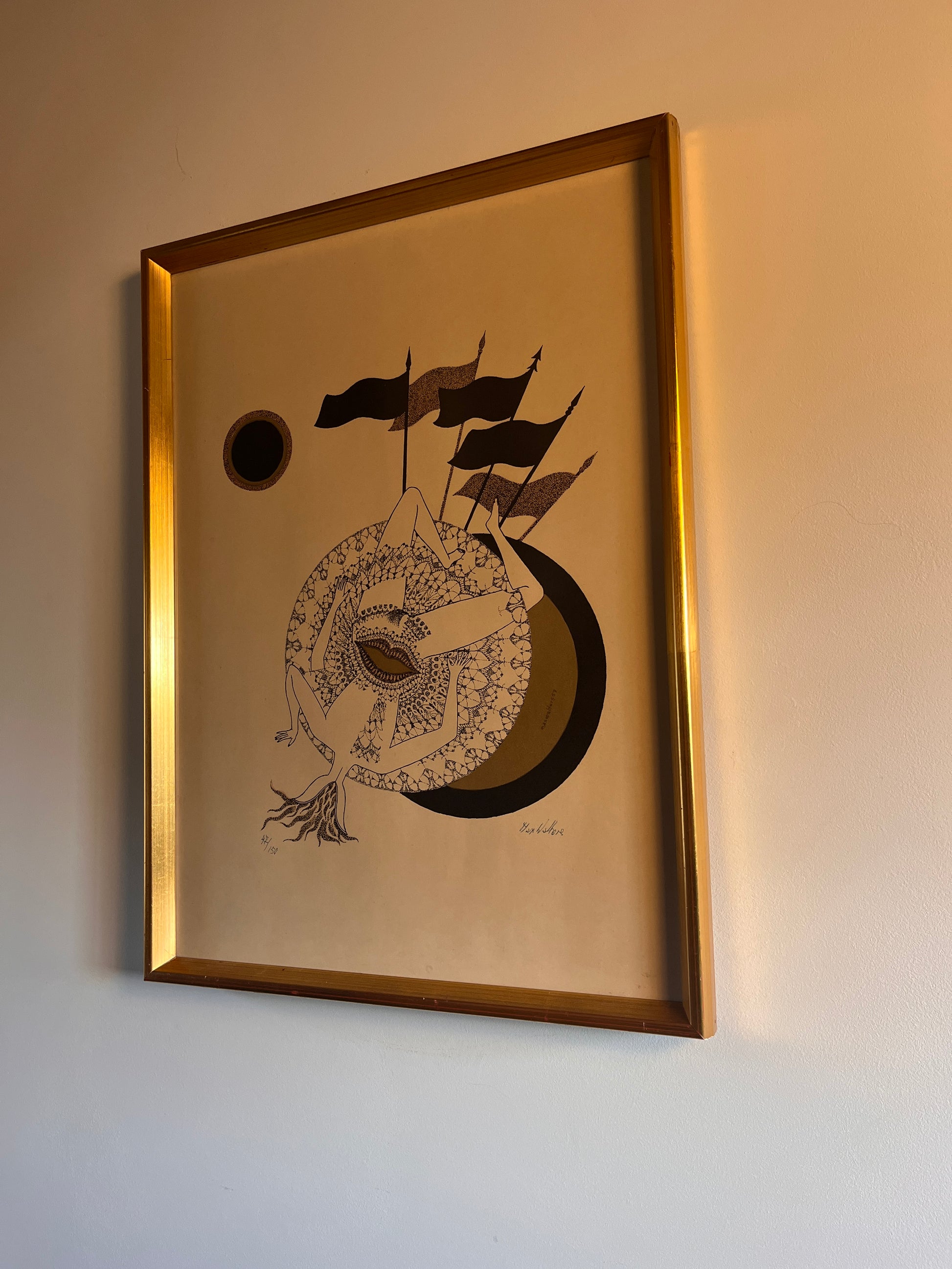 lithograph in a gold frame on a neutral wall