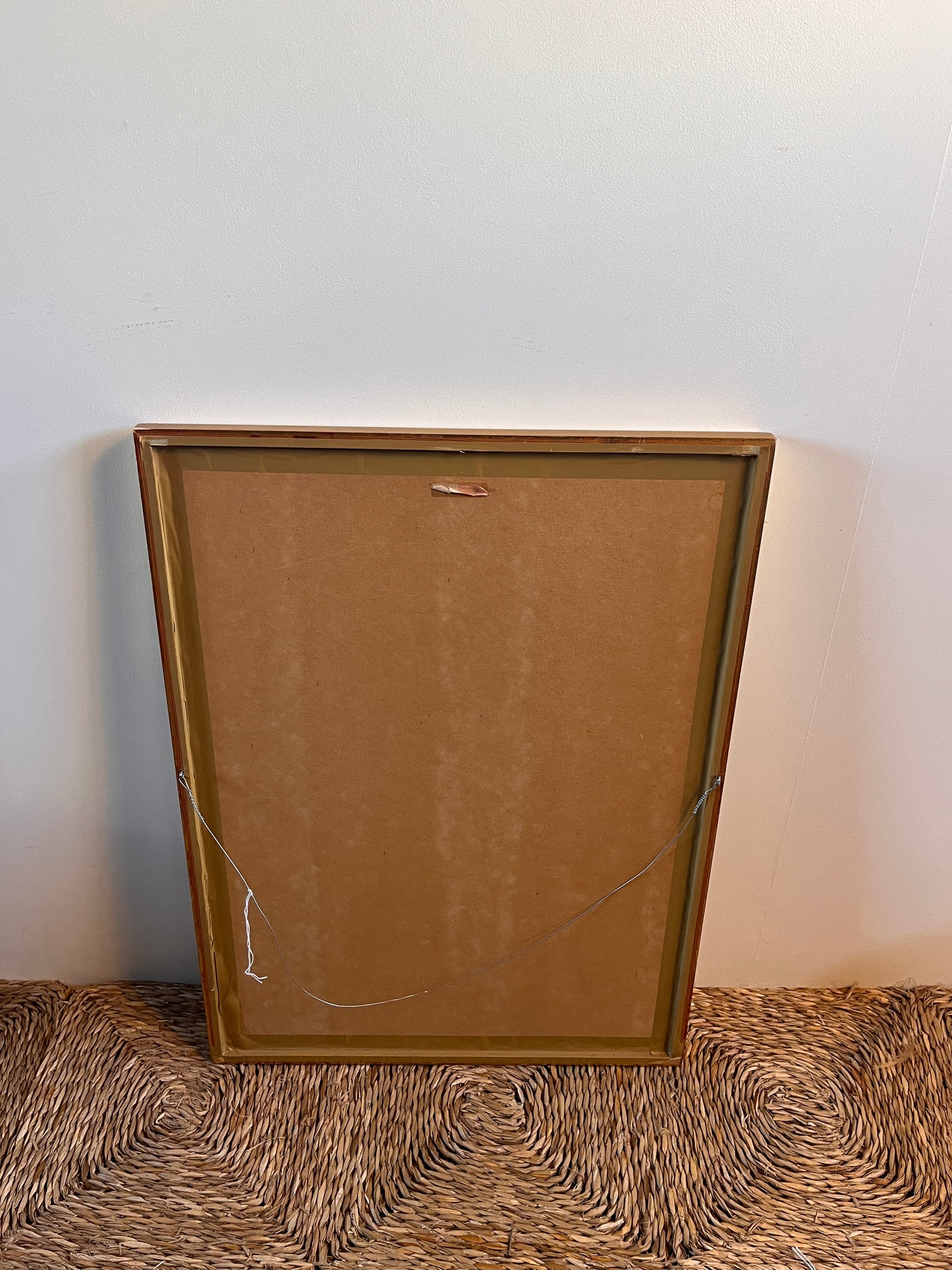 back of a brown frame standing on the floor with a white wall background