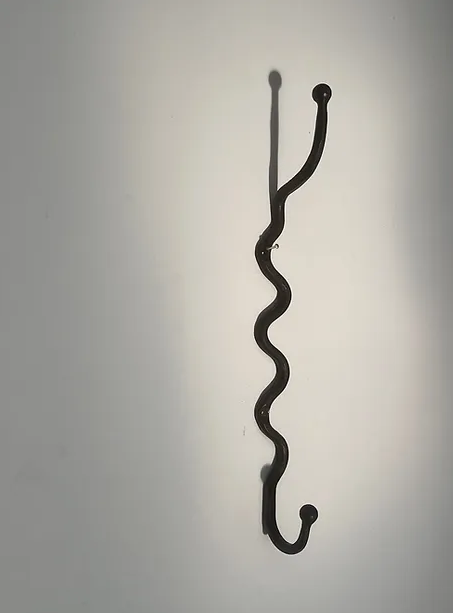 Black iron wiggle hook, a wavy hook hanging on a wall ready to hold a towel or and and coat